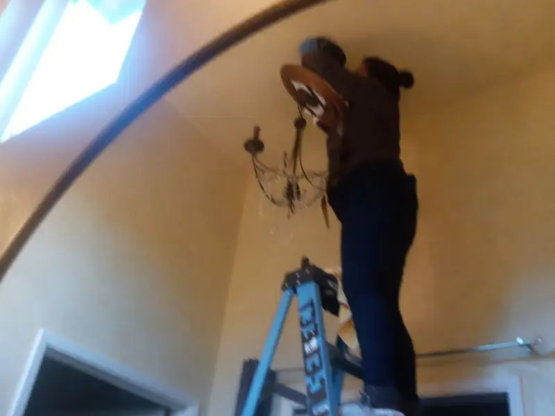 Electrician installing a chandelier in a Connerton residence